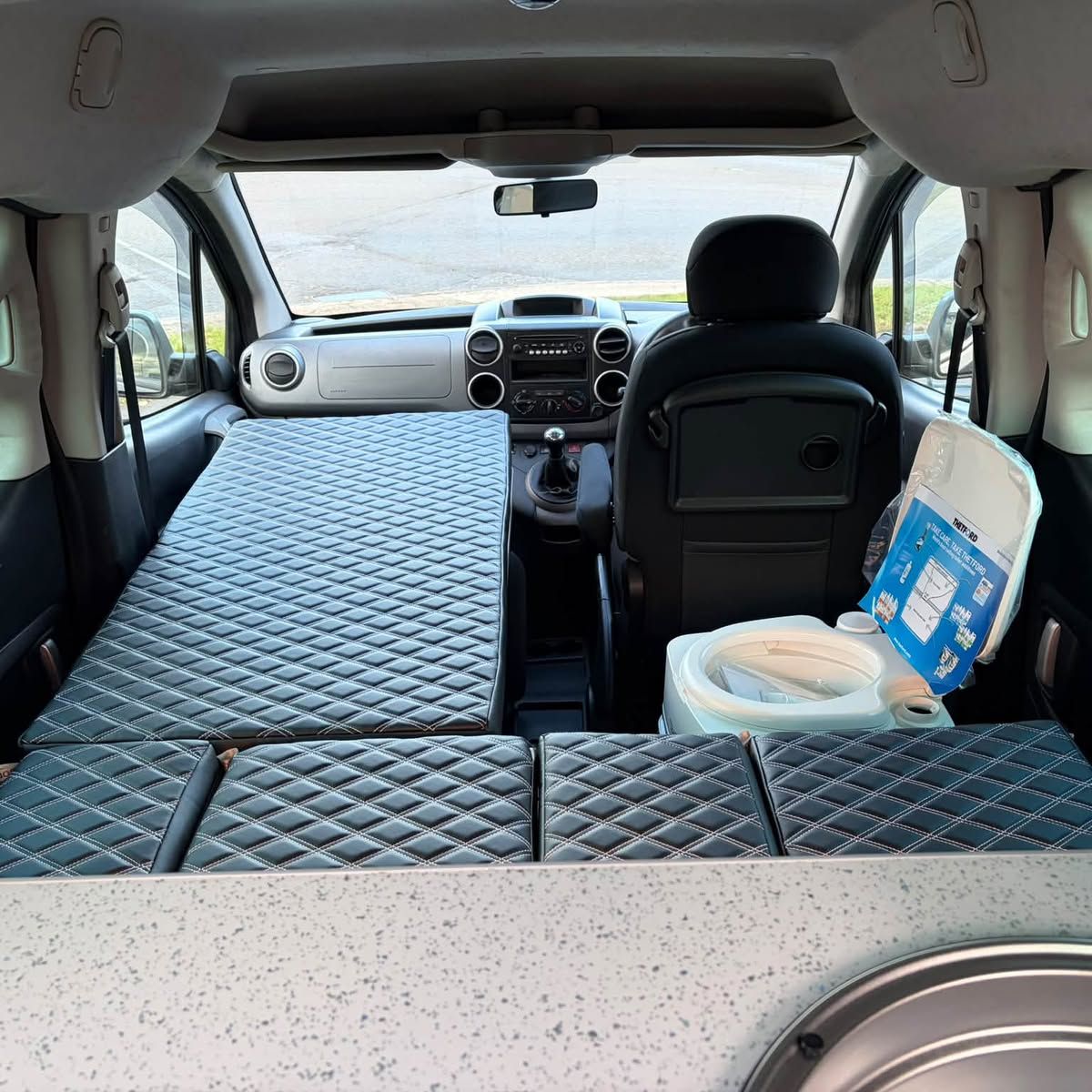 Looking forward from a quilted bed toward the front seats, with a compact sink at the side.